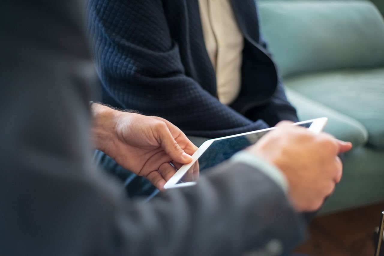 Two business people using a tablet during an indoor meeting. Perfect for tech and collaboration themes.